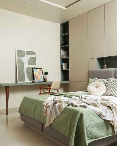 Bedroom with sage green bedding, beige wardrobe wall, and green-backed built-in bookshelf