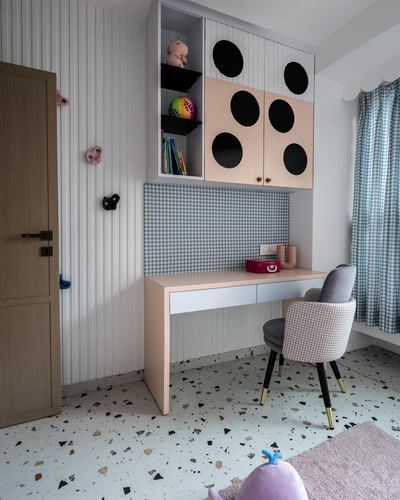 Child's study nook with peach desk, polka-dot cabinets, gingham wall, and terrazzo floor