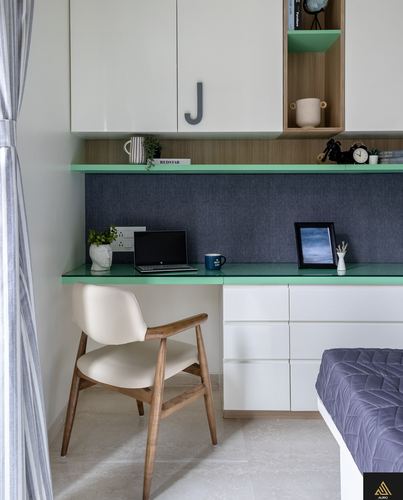 Small white and green study nook with wood chair, laptop, and navy fabric backsplash beside a bed
