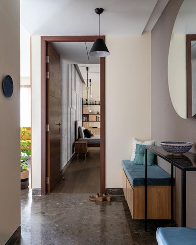 Foyer with marble floor, wooden bench, round mirror, and view through door into bedroom