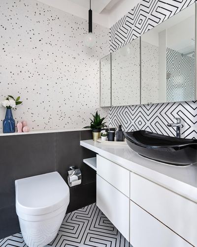 Black and white patterned bathroom with terrazzo wall, black vessel sink, and white vanity.