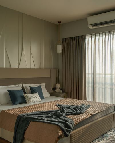Bedroom with textured grey wall panel, upholstered headboard, and teal throw on tan quilt