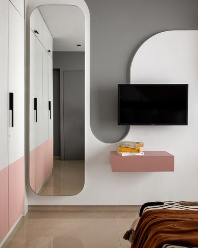 Bedroom wall with arched mirror, wardrobe, and TV niche in cream and pink tones