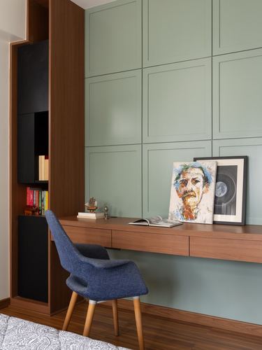 Study nook with floating wood desk against a sage-green panelled wall and blue chair