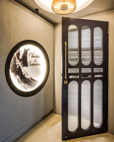 Entryway with dark fluted-glass door and backlit circular artwork on textured wall
