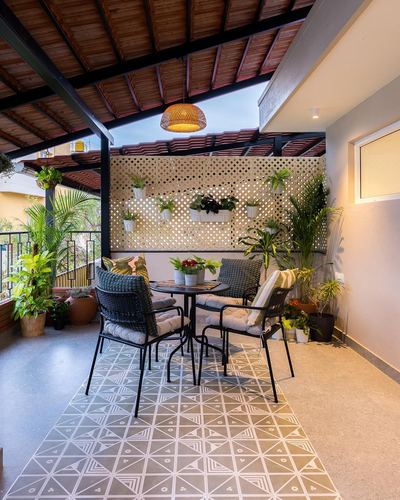 Covered terrace with terracotta roof, patterned tile floor, black bistro set and planter trellis wall