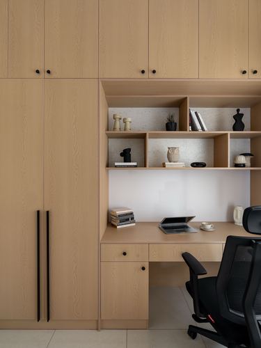 Built-in wooden study nook with open shelves, desk, laptop and black office chair