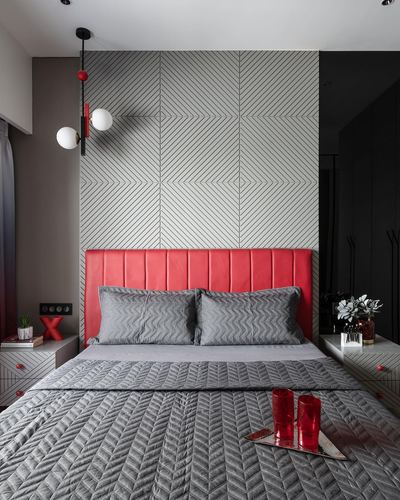 Bedroom with red tufted headboard, geometric grey wall panel, and globe pendant lights