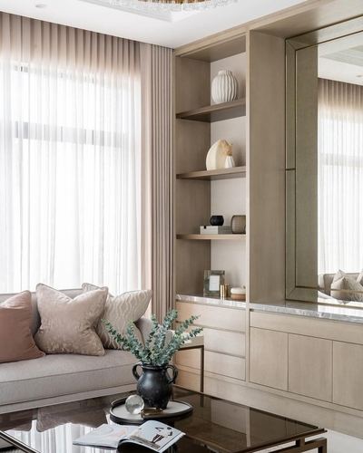 Living room corner with wood shelving, marble counter, sheer curtains and pink upholstered sofa
