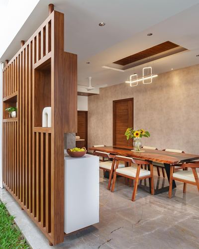 Wooden slatted partition beside a live-edge dining table with pendant lights in a Bangalore home