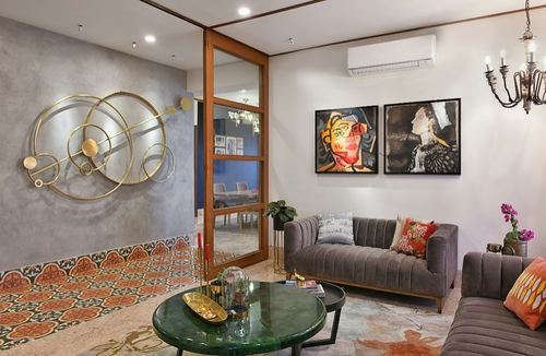 Living room with velvet sofas, green marble table, patterned tile floor and gold wall sculpture