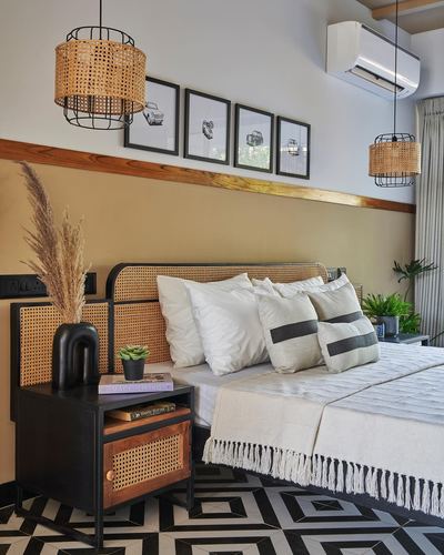 Bedroom with cane headboard, mustard wall, black nightstand, and geometric tile floor