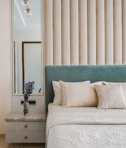 Bedroom corner with fluted cream headboard wall, teal base, mirror and marble-top nightstand