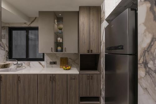 Modern kitchen with wood cabinetry, marble-look stone wall, and stainless steel refrigerator