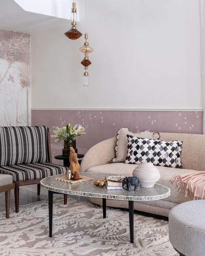 Living room with curved beige sofa, patterned cushions, inlay coffee table, and amber pendant lights