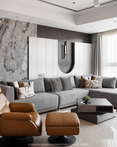 Contemporary living room with grey sectional, tan leather recliner, and fluted paneling with brass sconce