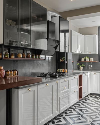 Black and white kitchen with glass cabinets, brass hardware, and geometric tiled floor