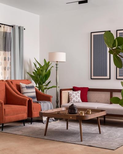 Living room with rust armchair, cane sofa, wood coffee table, framed textile art and floor lamp