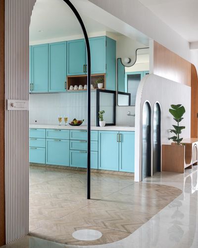 View through arched doorway into turquoise kitchen with herringbone and marble flooring