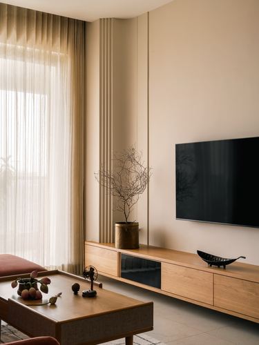 Warm minimalist living room with fluted paneling, wood tv console, and sheer curtained window
