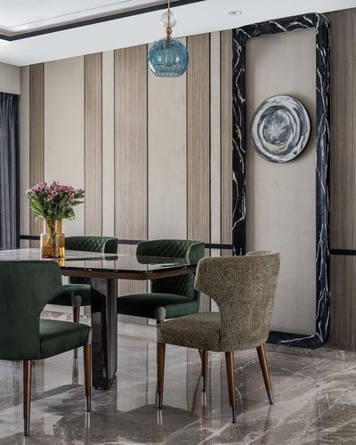 Dining room with green velvet chairs, marble table, and black marble-framed wall niche