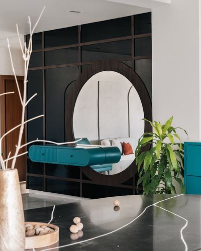 Foyer with dark grid paneling, oval mirror, and teal floating console beside marble counter