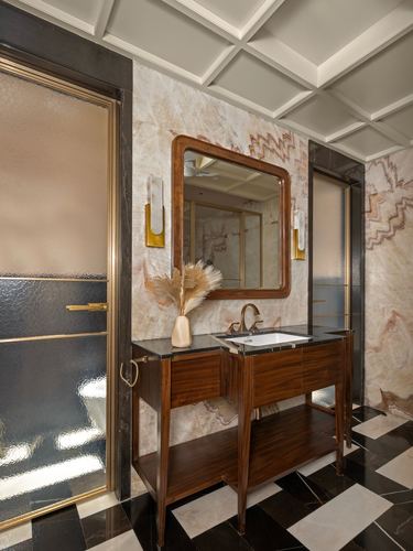 Bathroom vanity with wooden cabinet, veined stone wall, brass sconces, and diamond marble floor