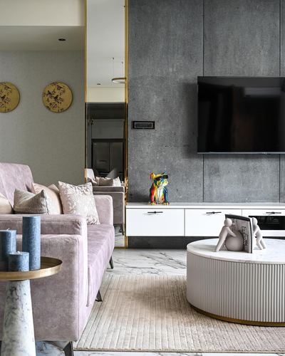 Living room with pink velvet sofa, grey stone TV wall, and round fluted marble coffee table