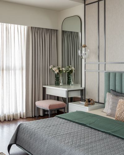 Bedroom corner with dressing table, arched mirror, pink stool and green upholstered headboard