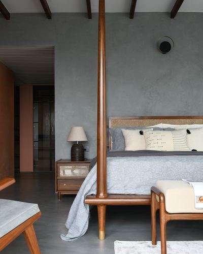 Bedroom with wooden four-poster bed, cane headboard, and lime plaster grey walls