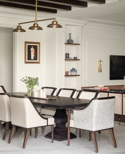Formal dining room with dark wood table, cream upholstered chairs, brass pendant, and display niche