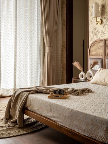 Bed with cane arched headboard, floral wallpaper, sheer curtains and morning light
