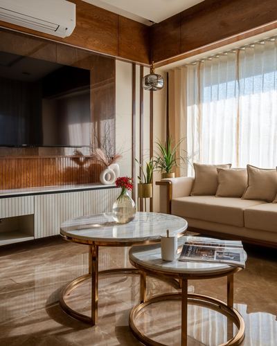Living room with wood-panelled TV wall, beige sofa, and round marble nesting tables