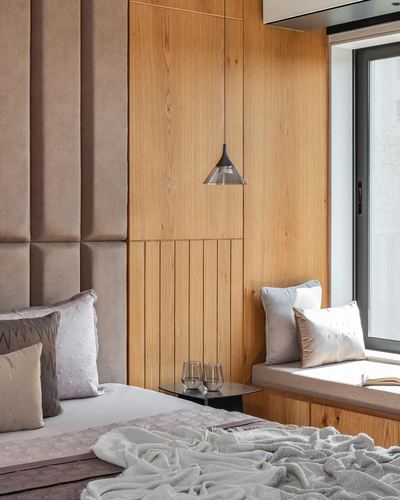 Bedroom with padded headboard, wood-panelled wall, pendant light and window seat with cushions