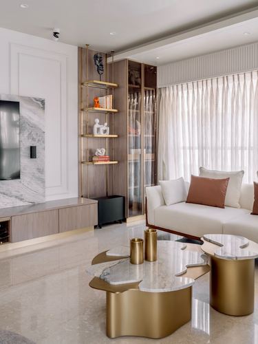 Living room with brass shelving, marble accent wall, and organic-shaped marble coffee tables