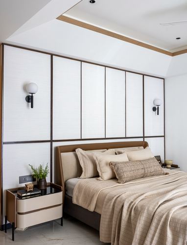 Bedroom with paneled wood wall, globe sconces, and beige upholstered bed