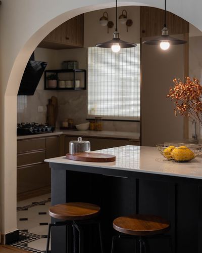 Arched doorway framing a kitchen island with pendant lights and wooden stools
