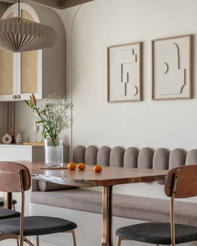 Dining nook with scalloped bench, live-edge wooden table, and framed abstract reliefs on wall