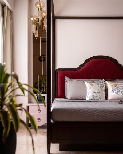 Bedroom with dark wood four-poster bed, red velvet headboard, chandelier reflected in mirror panel