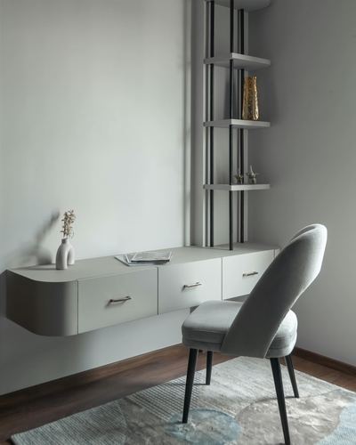 Floating curved desk with black ladder shelf and upholstered chair in a minimalist study nook