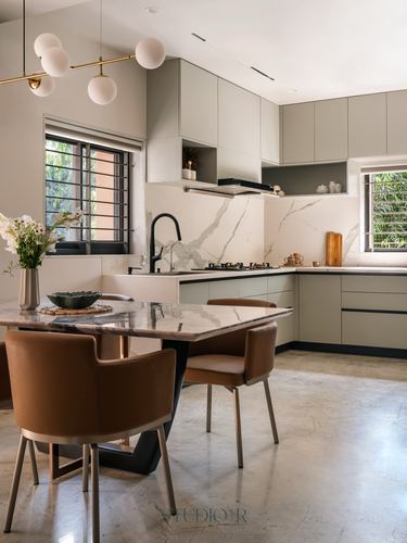 Open kitchen and dining area with sage cabinetry, marble backsplash, and brass globe pendant lights