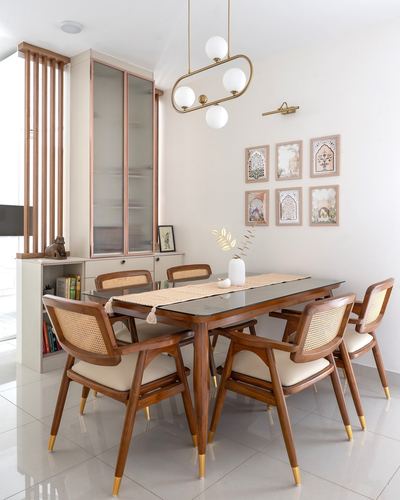Dining room with cane chairs, wood table, brass pendant light and framed art grid on wall