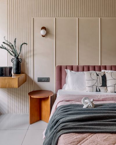 Bedroom with pink upholstered headboard, fluted panel wall, and floating wood nightstand