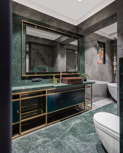 Green and grey marble bathroom with brass-framed vanity, mirror, copper sink and freestanding tub