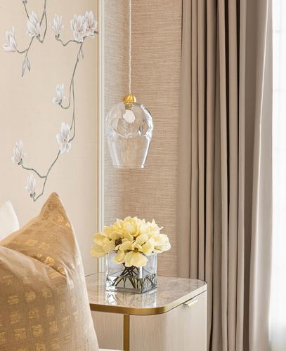 Bedside vignette with glass pendant light, floral mural, and marble-top nightstand with yellow flowers