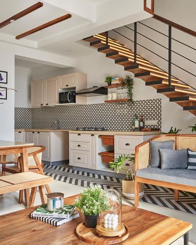 Open kitchen and living area with patterned tile backsplash and glowing floating staircase above