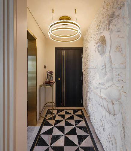 Foyer with sculpted Buddha wall mural, black door, brass console, and geometric marble floor inlay
