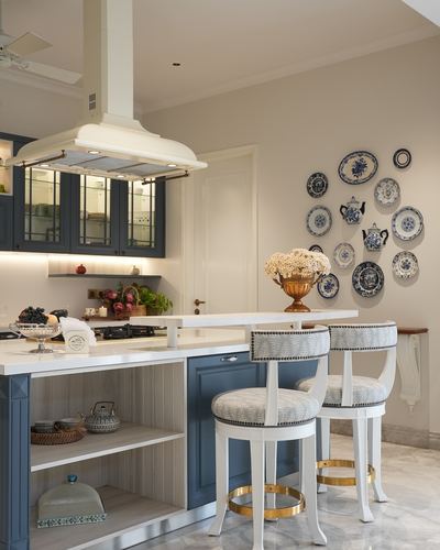 Kitchen island with blue cabinetry, upholstered bar stools, and a wall of blue-and-white decorative plates