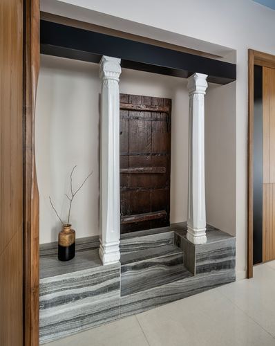 Foyer niche with white fluted columns flanking an old wooden door on a stone platform