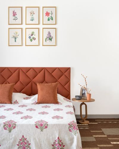 Terracotta diamond-tufted headboard bed with floral botanical print gallery wall above